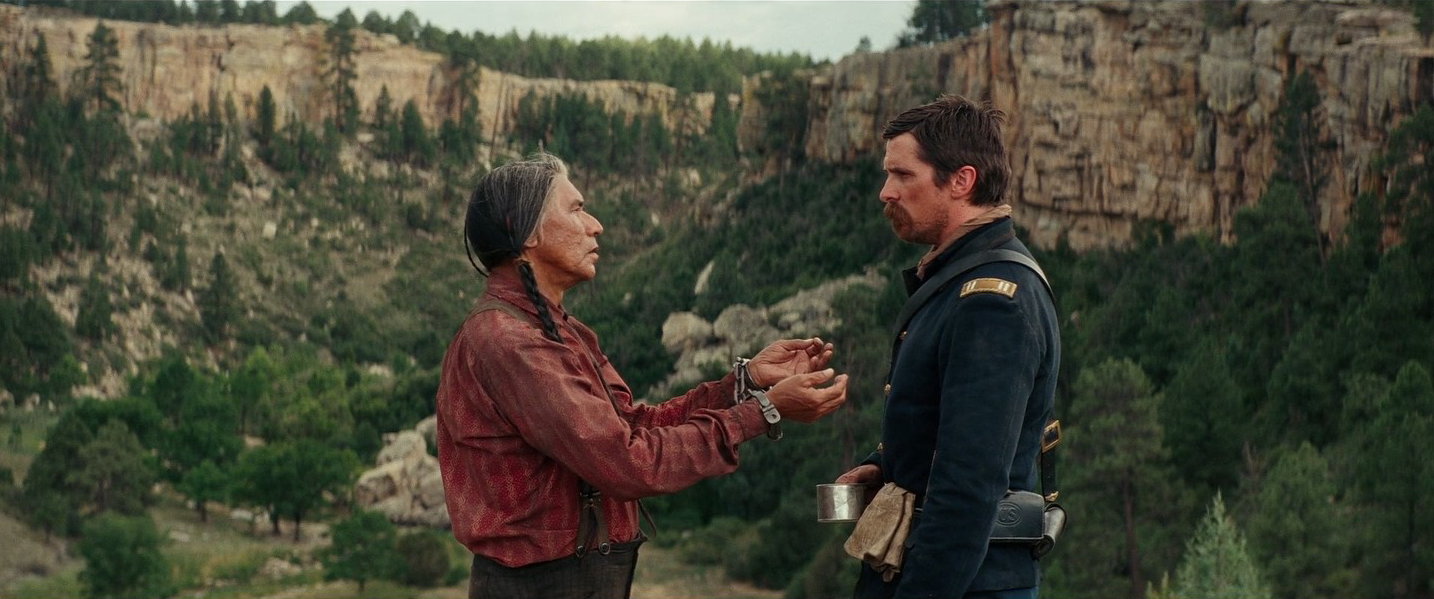 Chefe Falcão Amarelo (Wes Studi) e capitão Joseph J. Blocker (Christian Bale) conversando