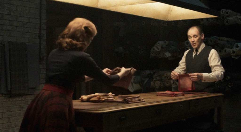 Mable e Leonard dobrando pedaços de panos enquanto conversam.