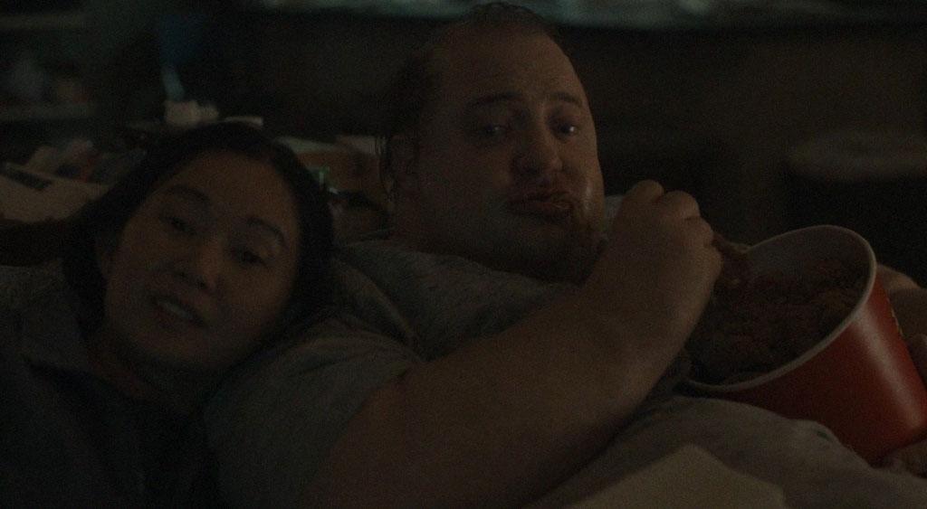 Liz (Hong Chau) e Charlie (Brendan Fraser) assistindo TV.