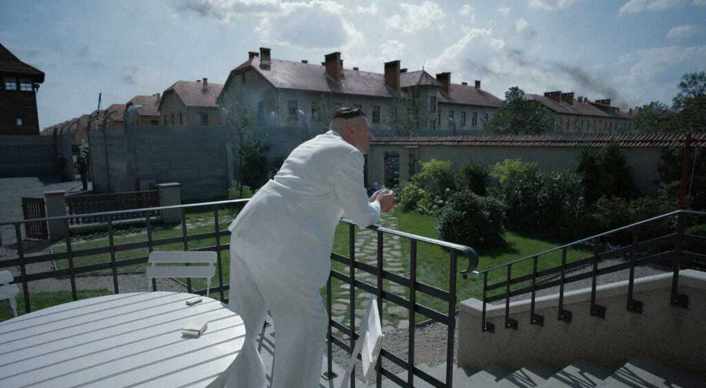 Rudolf Höss fuma um charuto debruçado na grade de sua sacada.