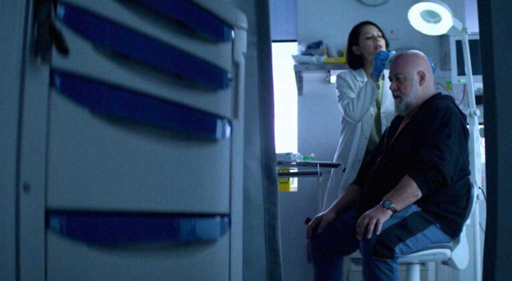 Dra. Margaret Xu examinando os curativos nas incisões feitas na cabeça de Roy Freeman.