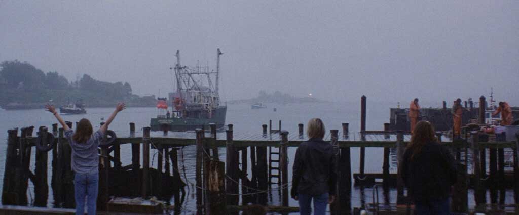 As mulheres e pessoas próximas correm para a beirada do piér e acenam em despedida para os pescadores que partem para a derradeira pesca.