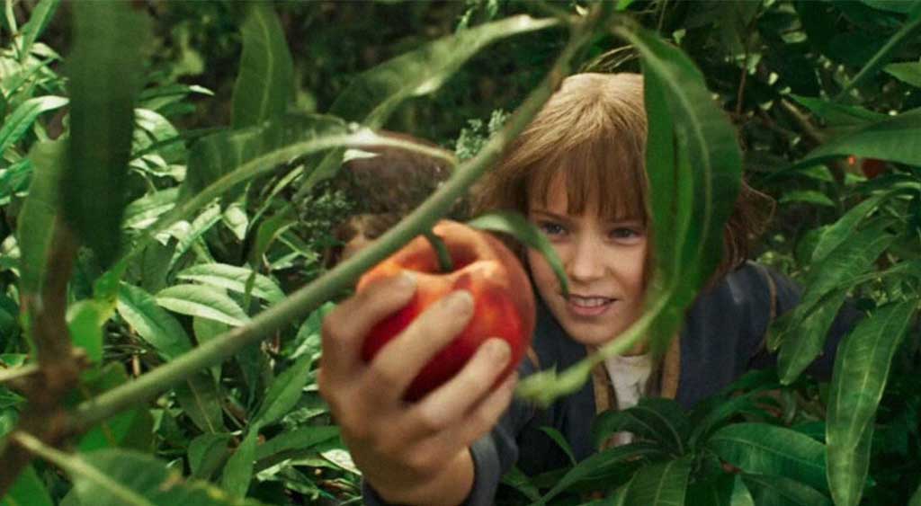 A jovem Furiosa (Alyla Browne) colhendo pêssego.