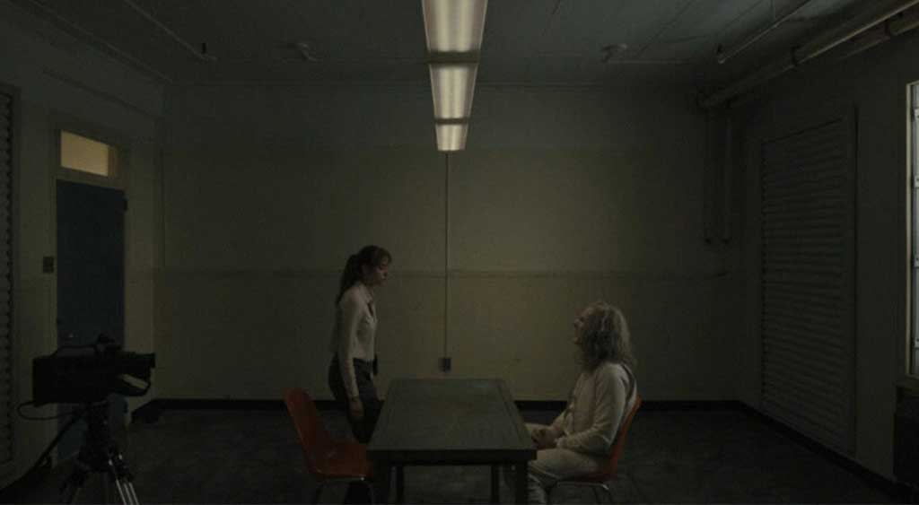 A agente Lee Harker chega à sala de interrogatório para confrontar o assustador Longlegs.