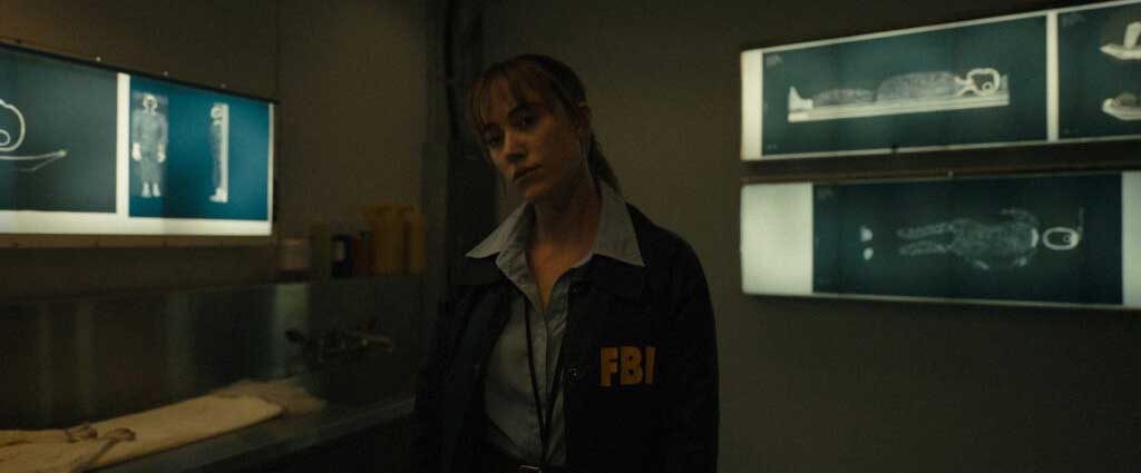 Agente Lee Harker tem o olhar distante após ver uma bola retirada da cabeça de uma boneca.