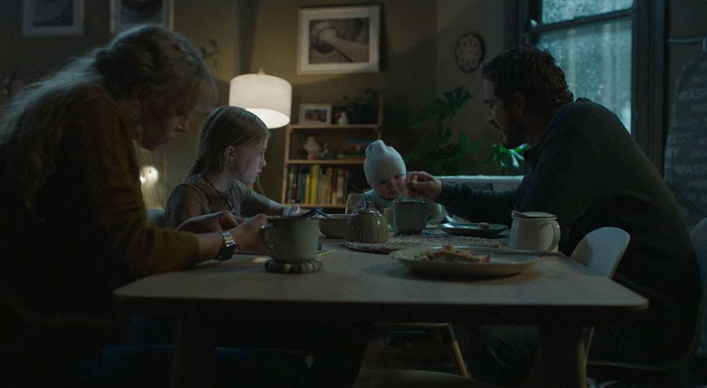 Charlotte setada à mesa com a família.