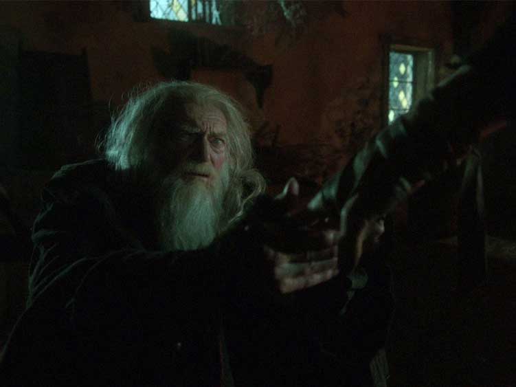 O homem cego pega a mão da Criatura que que está assustada ao deixar uma garrafa cair no chão e se quebrar.