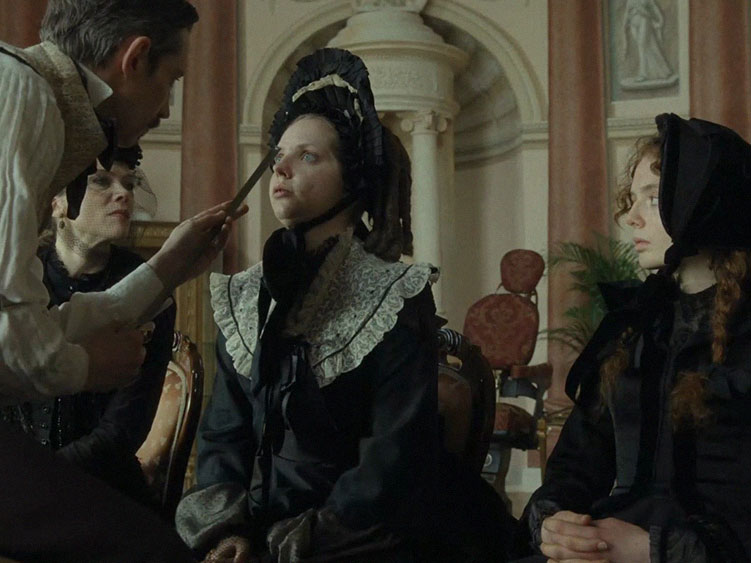 Dr. Esthétique tira a medida do nariz de Elvira com uma trena.