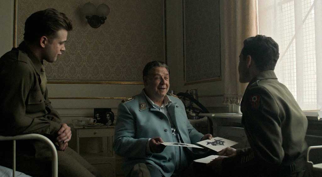 Hermann Göring sorri enquanto o psiquiatra Douglas Kelley faz a avaliação psicológica com o Teste de Rorschach. Sentado ao lado, o sargento Howard Triest os observa.