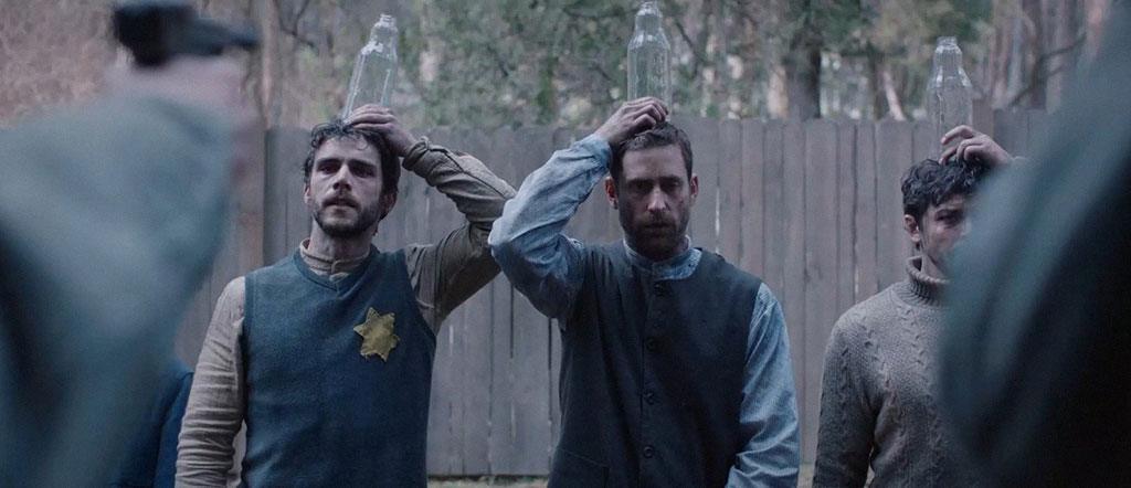 Michael, Solomon e Wolf sustentam uma garrafa de leite sobre as cabeças antes da doentia sessão de tiro ao alvo dos nazistas.