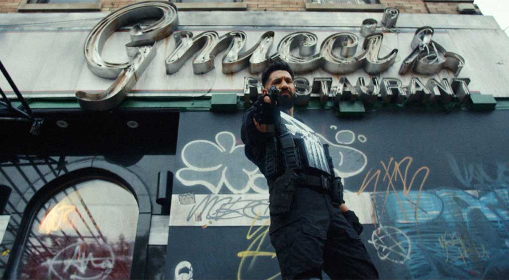 O Justiceiro (The Punisher) em ação, com a arma na mão e o meliante no chão.